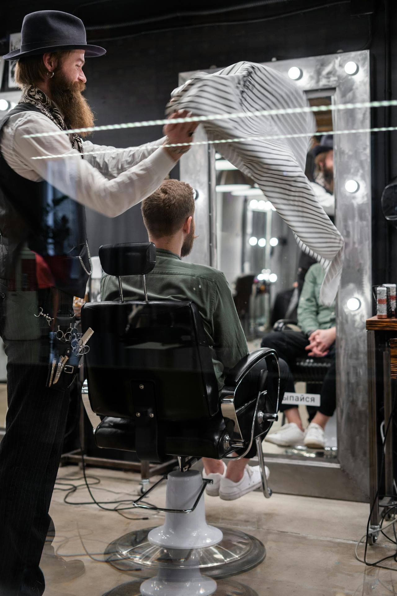 Barber finishing a client with a towel in a moody atmosphere