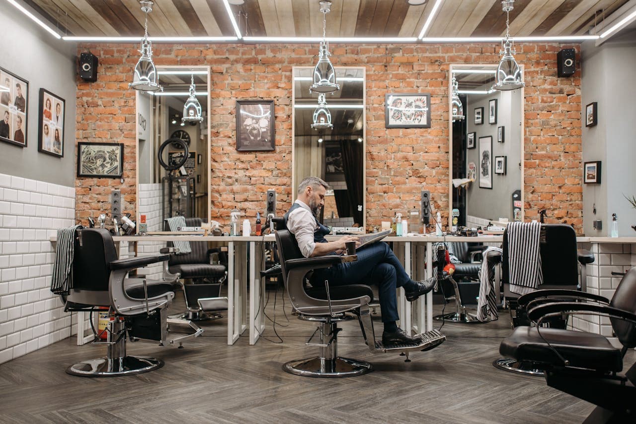 Wide barbershop interior with a seated client and warm lighting
