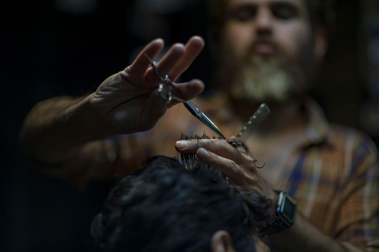 Barber trimming the fringe while misting the hair.