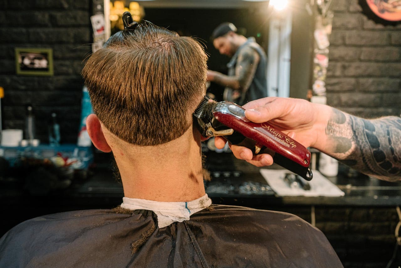 Barber finishing a haircut in strong side light.
