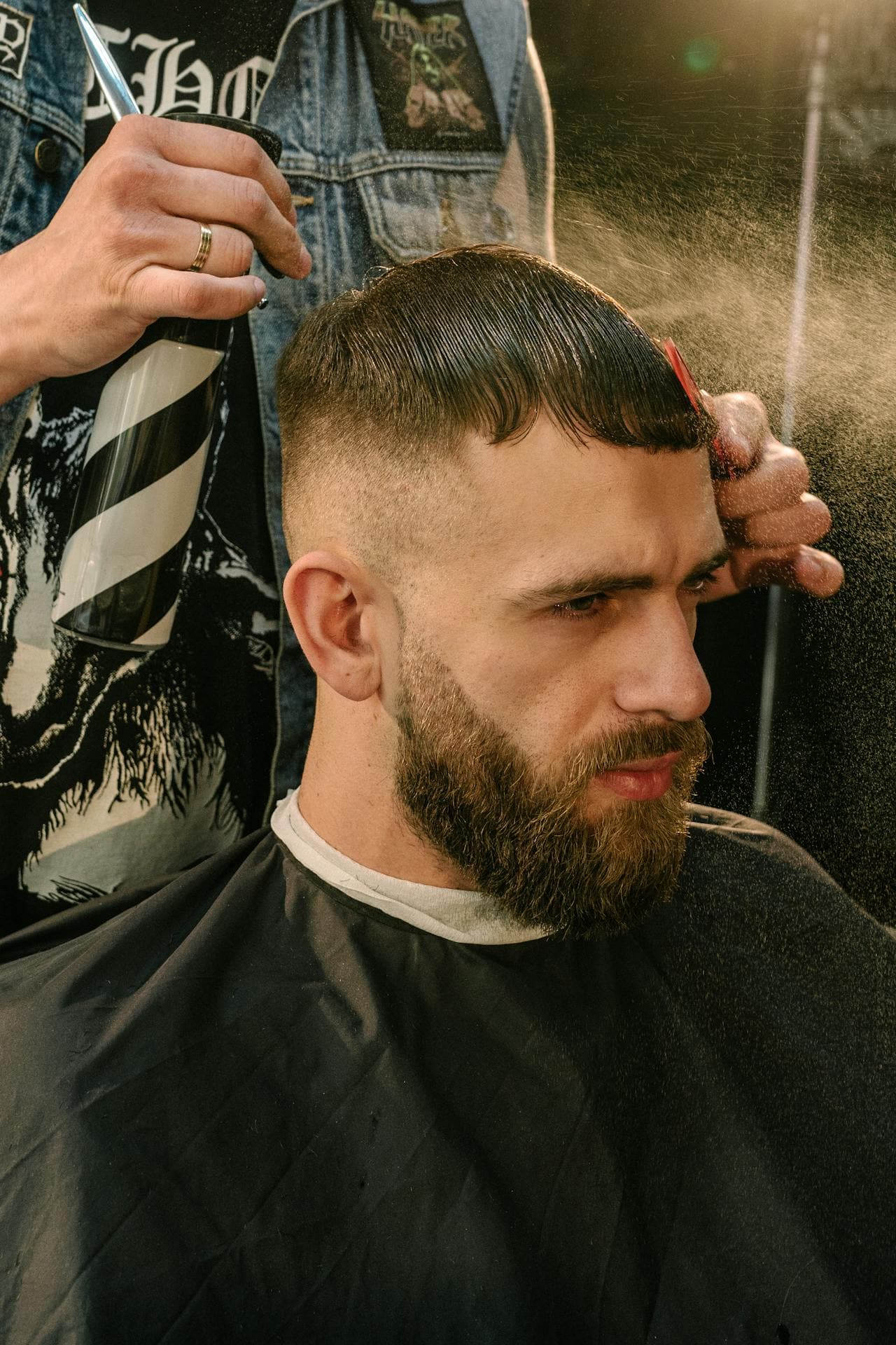 Barber trimming the beard while the client reclines.