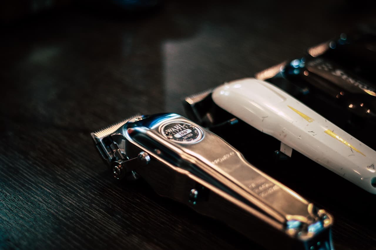 Barber clipper tools arranged on a dark work surface