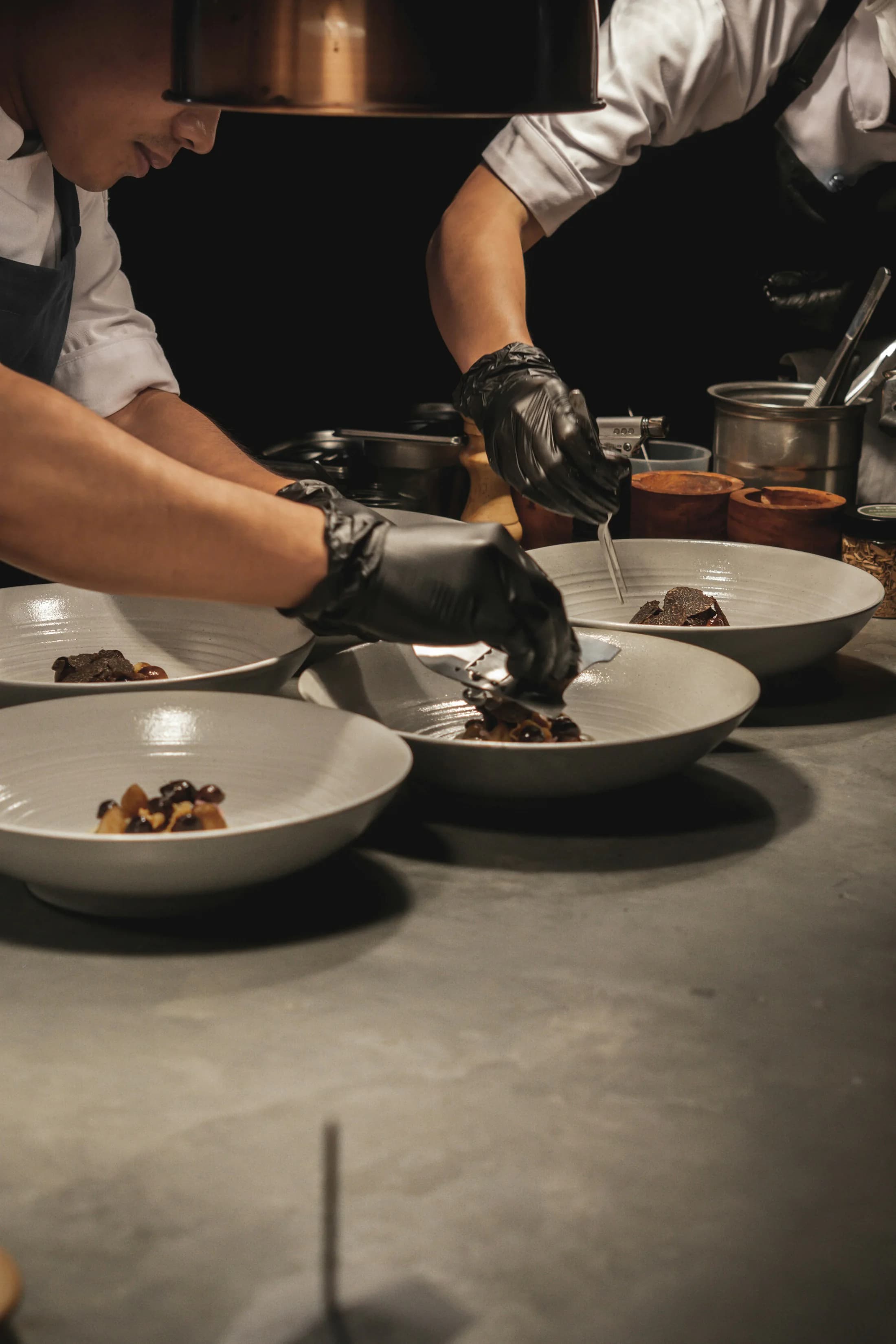 Two cooks plating dishes together at the pass