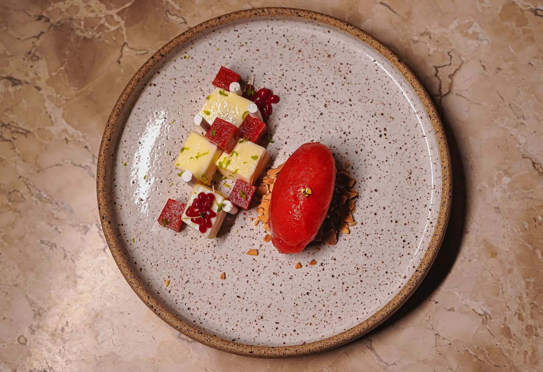 A fruit dessert with red sorbet on a ceramic plate