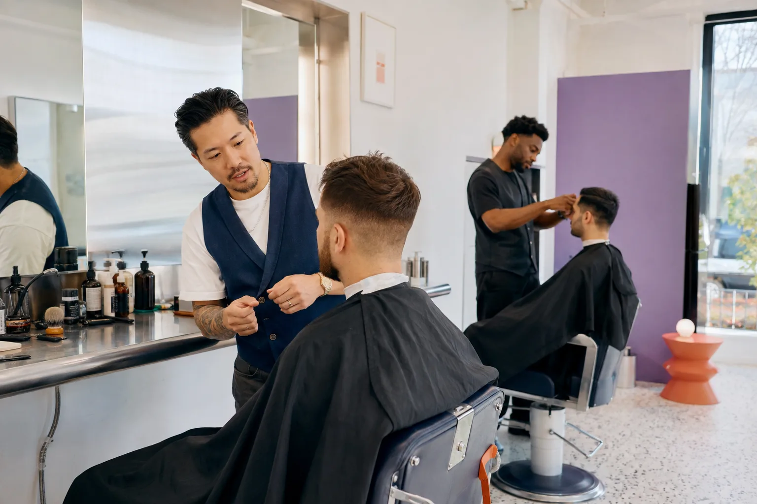 Barbers and clients sharing a bright, relaxed studio