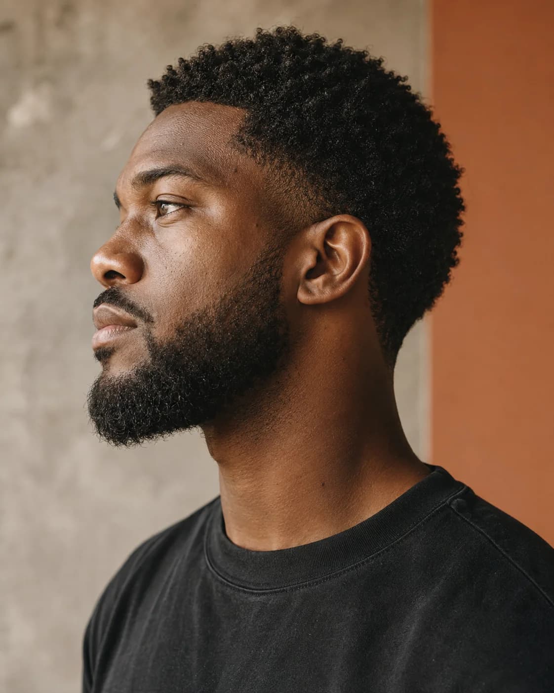 Natural curls and a shaped short beard in side profile